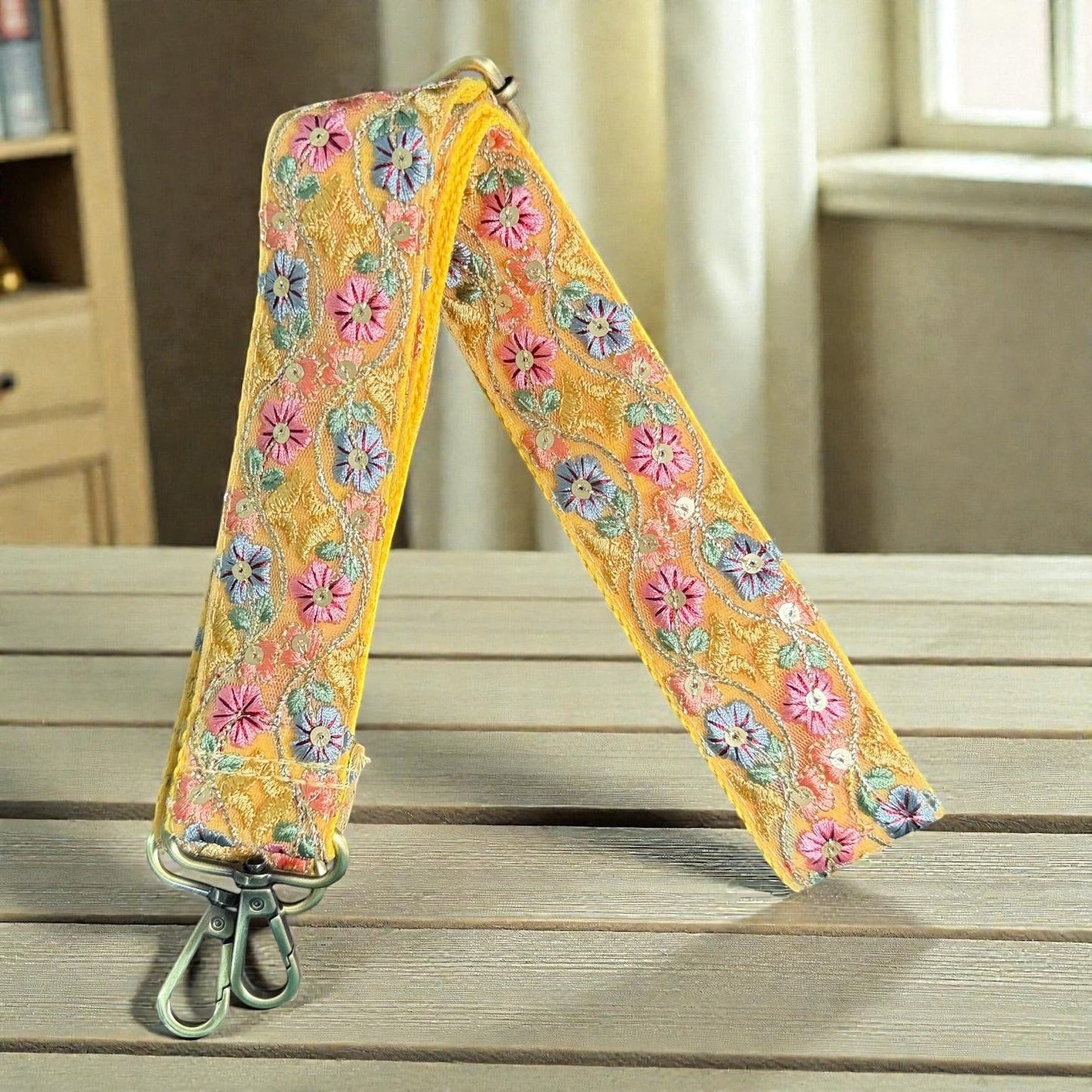 Rhea Artistry Studio yellow crossbody strap with floral embroidery in pink, blue, and green, featuring brushed brass hardware.