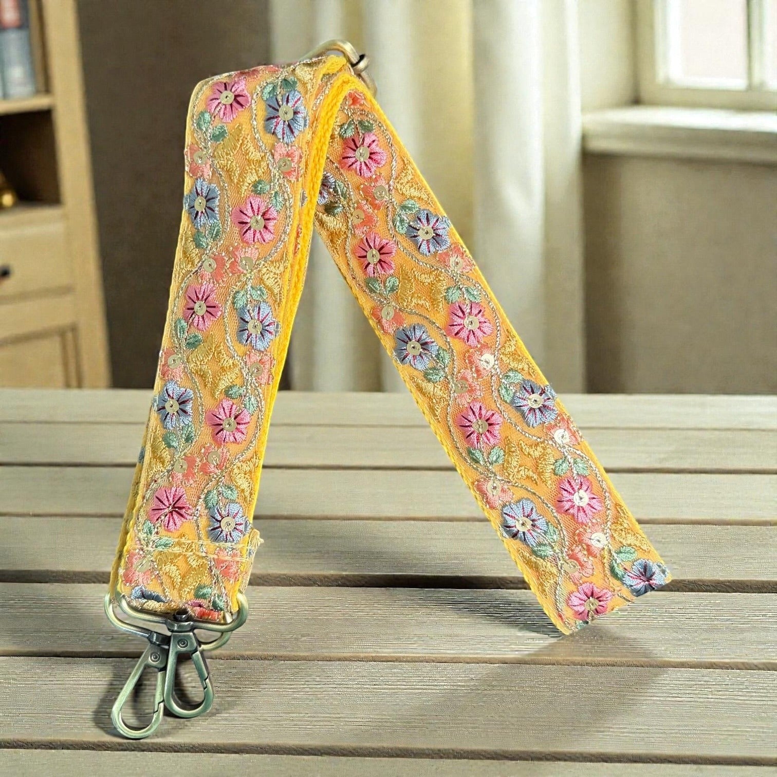 Rhea Artistry Studio yellow crossbody strap with floral embroidery in pink, blue, and green, featuring brushed brass hardware.
