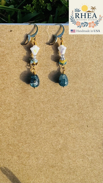 Rhea Artistry Studio white and silver floral glass bead drop earrings with blue gemstone and 24k gold-plated lever-back closures.