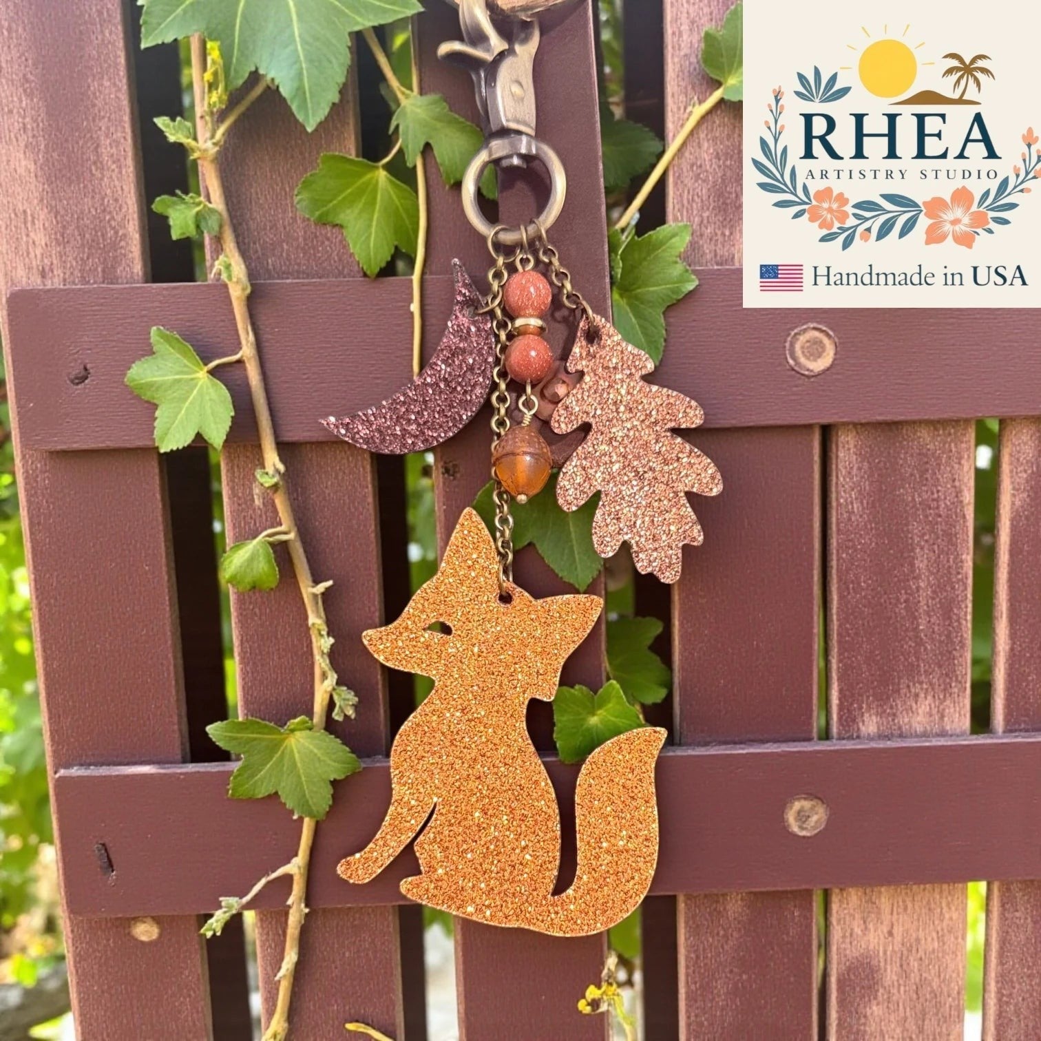 Rhea Artistry Studio handmade glitter leather fox charm with moon, oak leaf, acorn, and beads. Antique brass hardware.