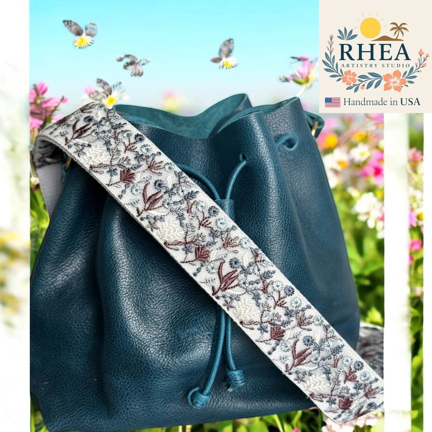 Rhea Artistry Studio 2-inch crossbody strap with embroidered frosted flora pattern in white, blue, and brown. Adjustable strap with brushed brass hardware.