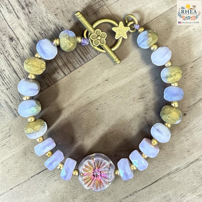 Rhea Artistry Studio handmade garden glass bead bracelet with lilac, peach, and gold beads, and a floral focal element.