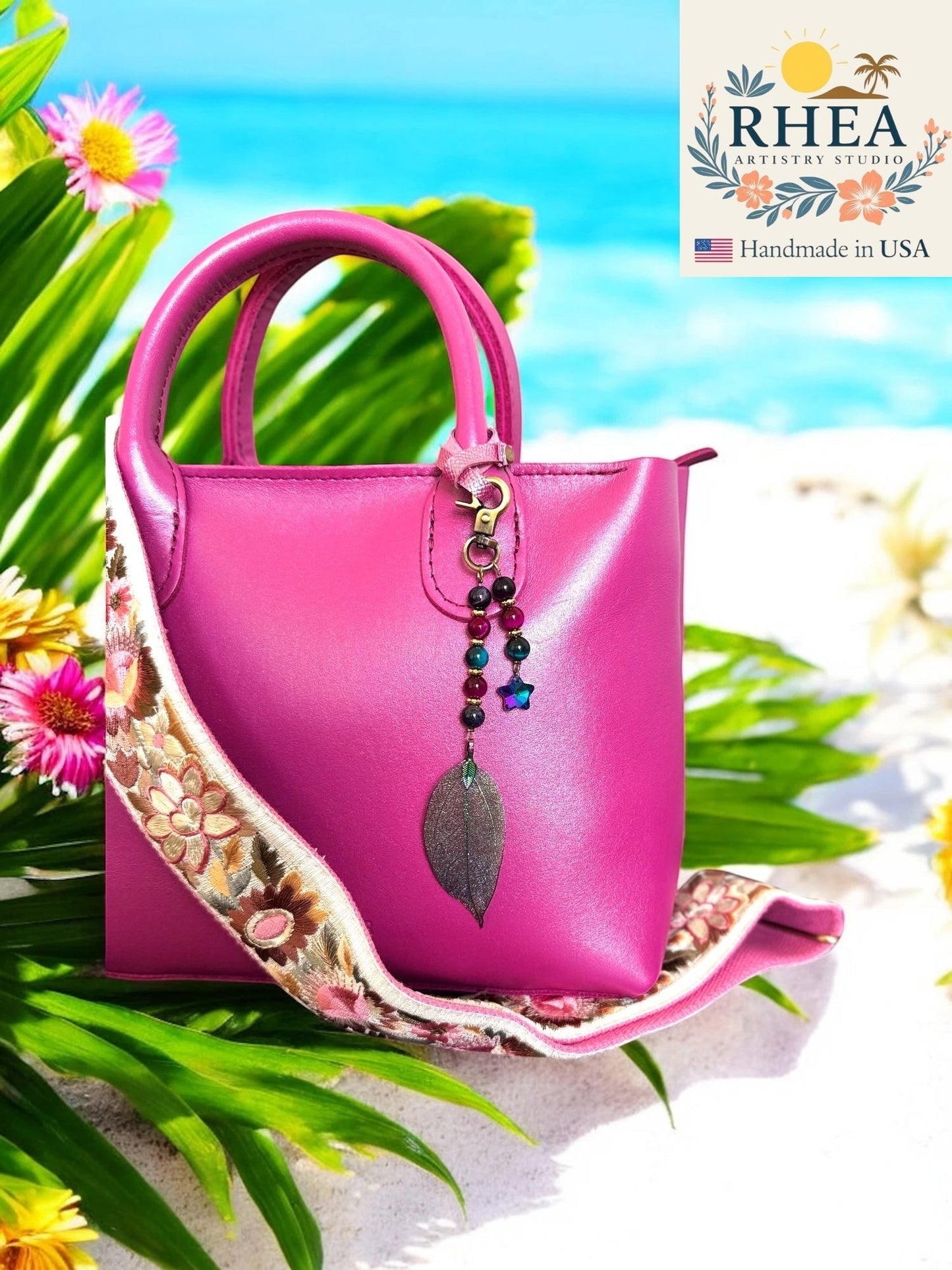 Rhea Artistry Studio fuchsia leather handbag with a handmade charm featuring galaxy gemstone beads and an iridescent electroplated leaf pendant.