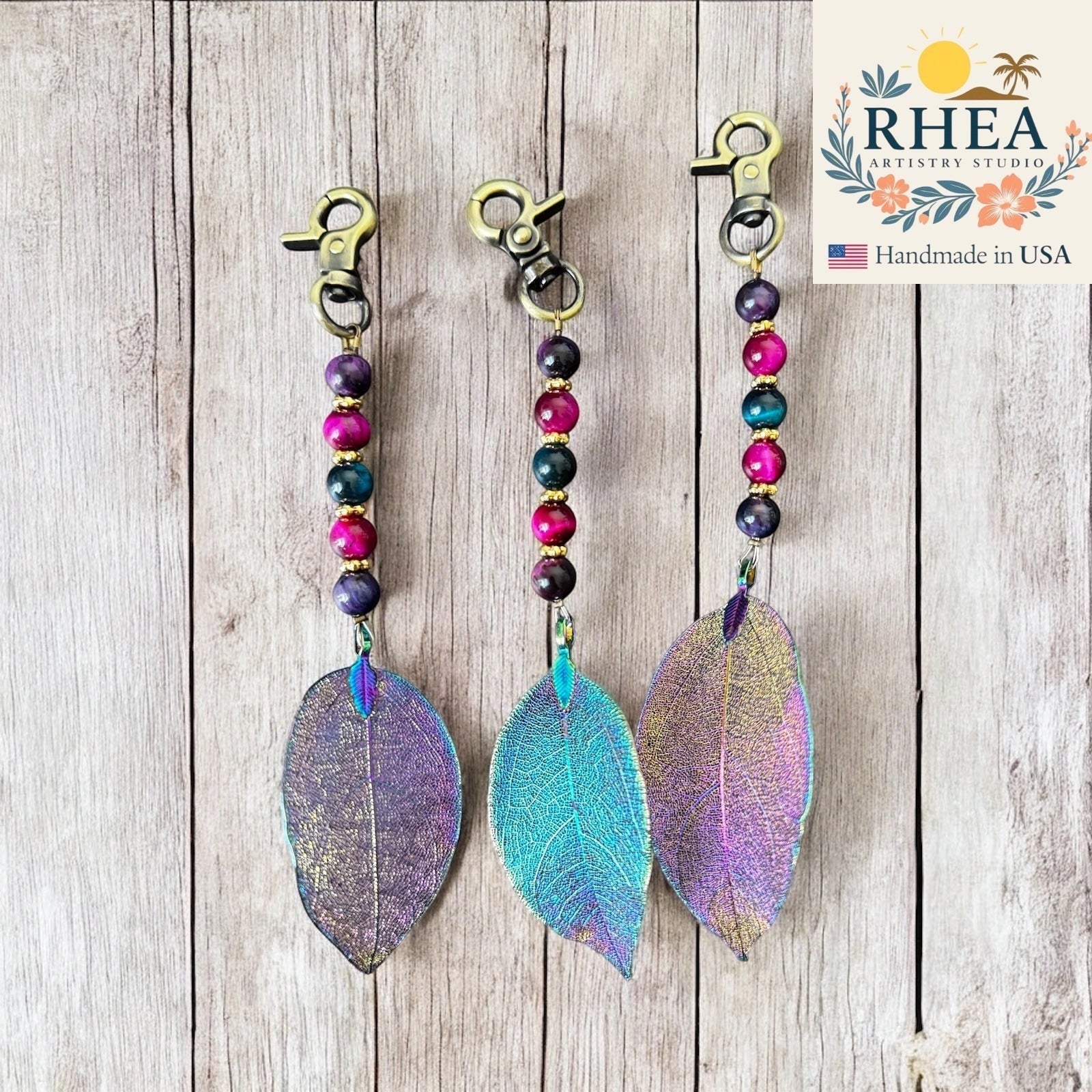Rhea Artistry Studio handmade bag charm with galaxy gemstone beads and iridescent electroplated leaf pendant, antique bronze clasp.