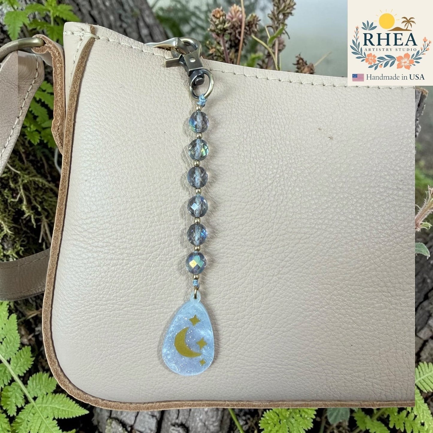 Rhea Artistry Studio bag charm with multi-faceted glass beads and a light blue pendant featuring a moon and stars.