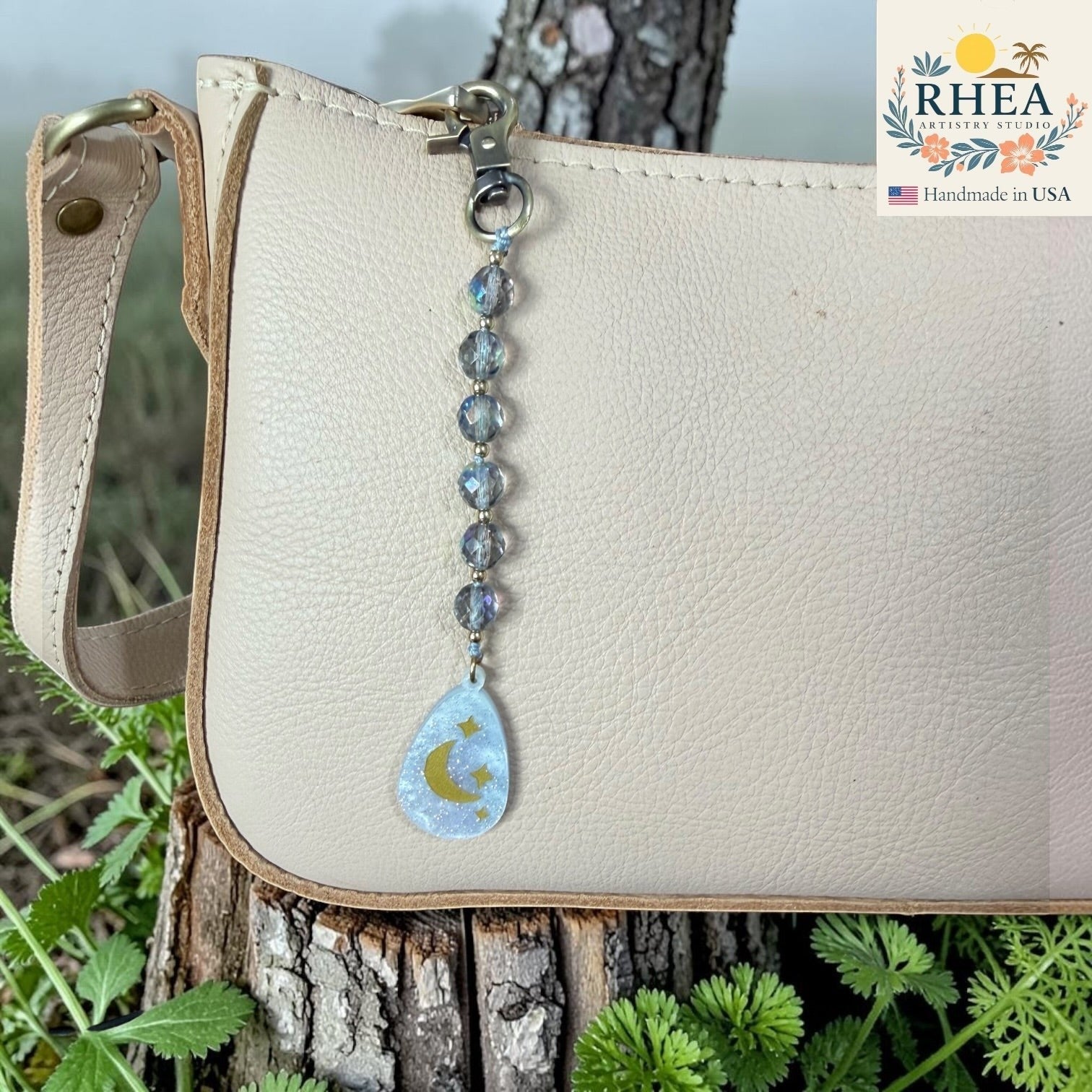 Rhea Artistry Studio handcrafted bag charm with iridescent glass beads and a moon and stars pendant. Brass hardware.