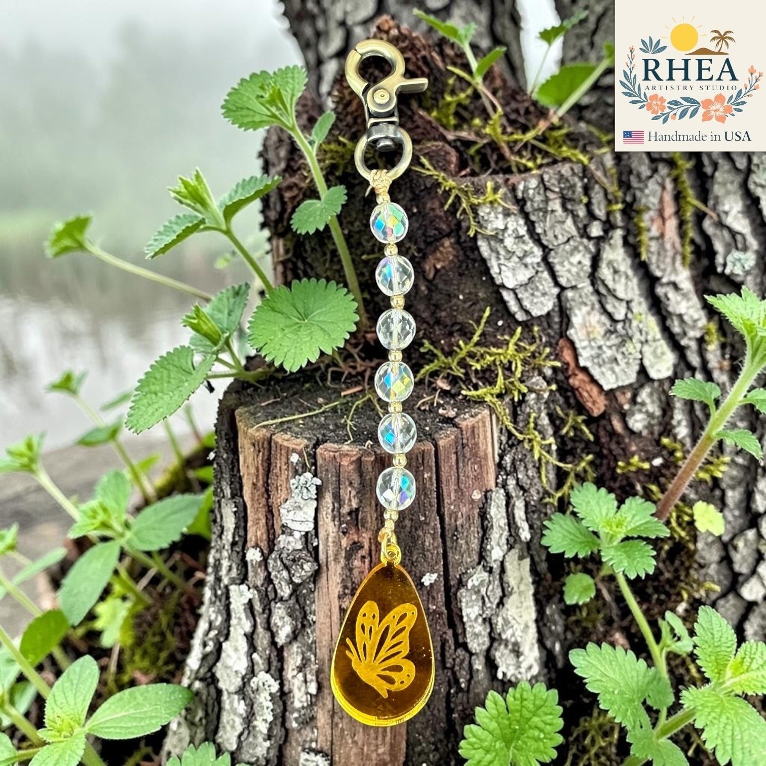 Rhea Artistry Studio handcrafted bag charm with clear AB finish glass beads and a yellow butterfly pendant on brass hardware.