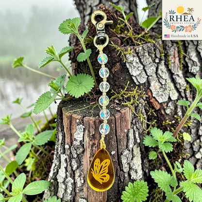 Rhea Artistry Studio handcrafted bag charm with clear AB finish glass beads and a yellow butterfly pendant on brass hardware.