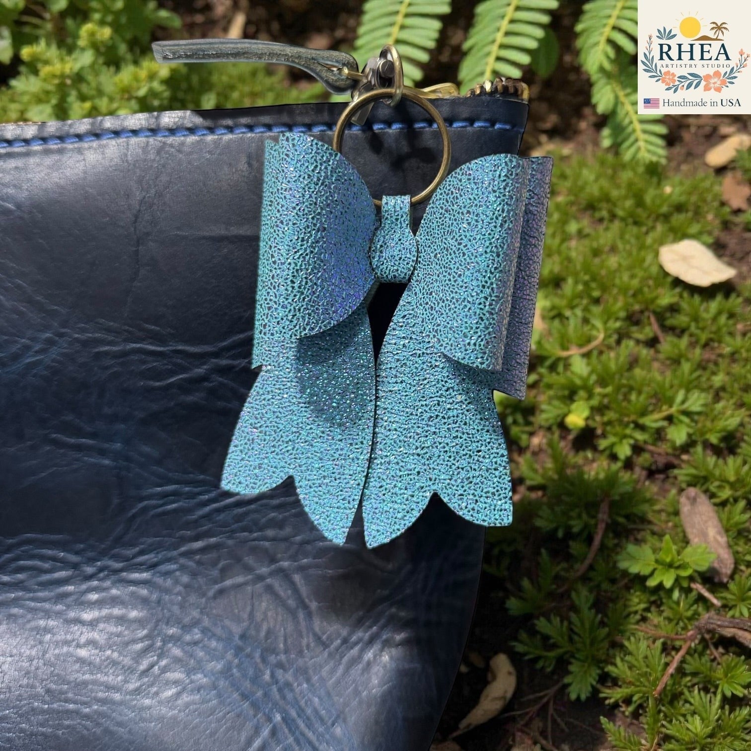 Rhea Artistry Studio handmade glittery teal double-layer French bow bag charm with brass hardware.