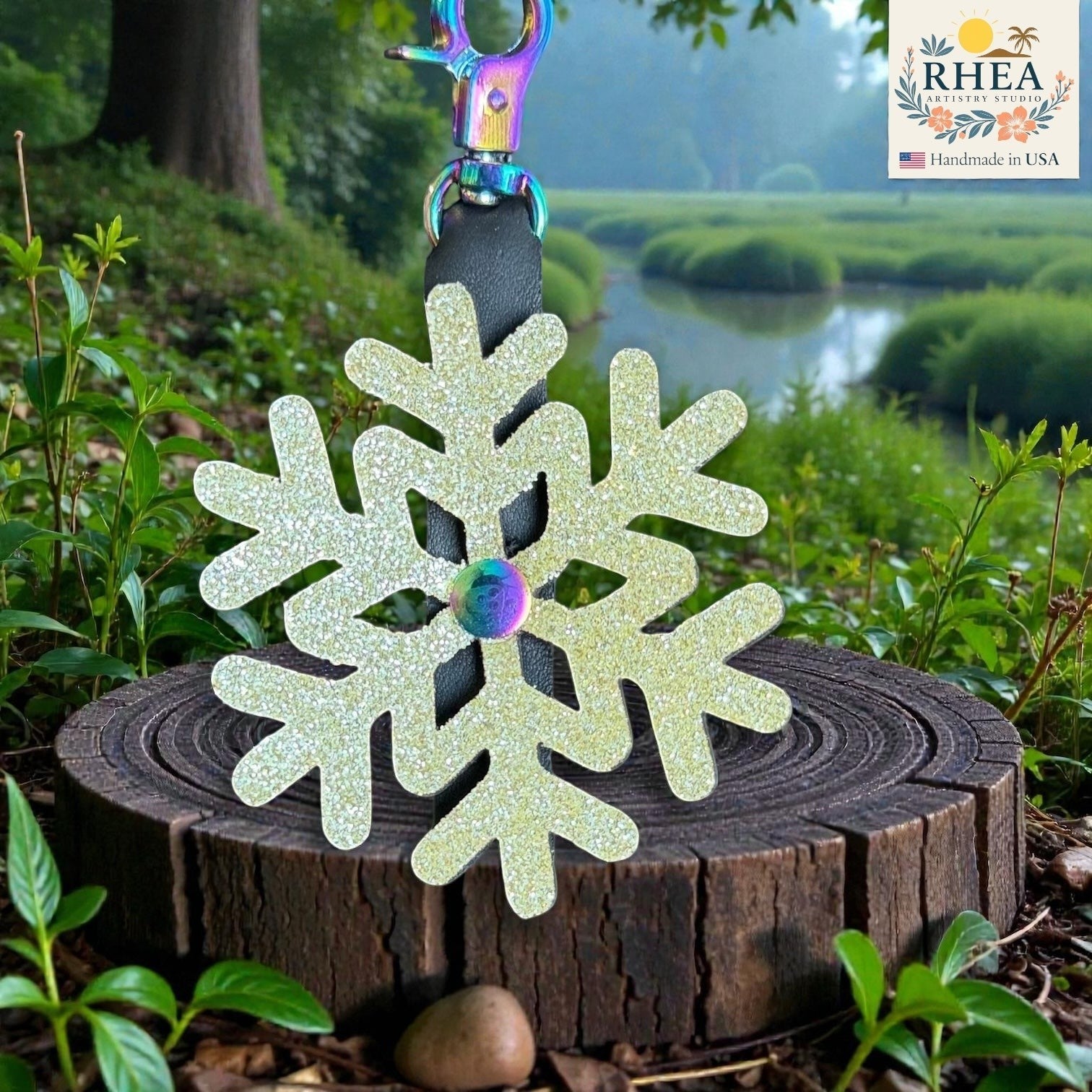 Rhea Artistry Studio glitter snowflake mini charm, handmade from shimmering leather with a rainbow accent. Attaches to bags, zippers, and keychains.