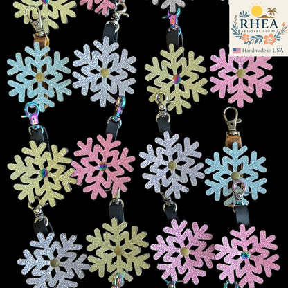 Rhea Artistry Studio glitter snowflake mini charms in pastel blue, silver, yellow, and pink, made from leather with a shimmering finish.