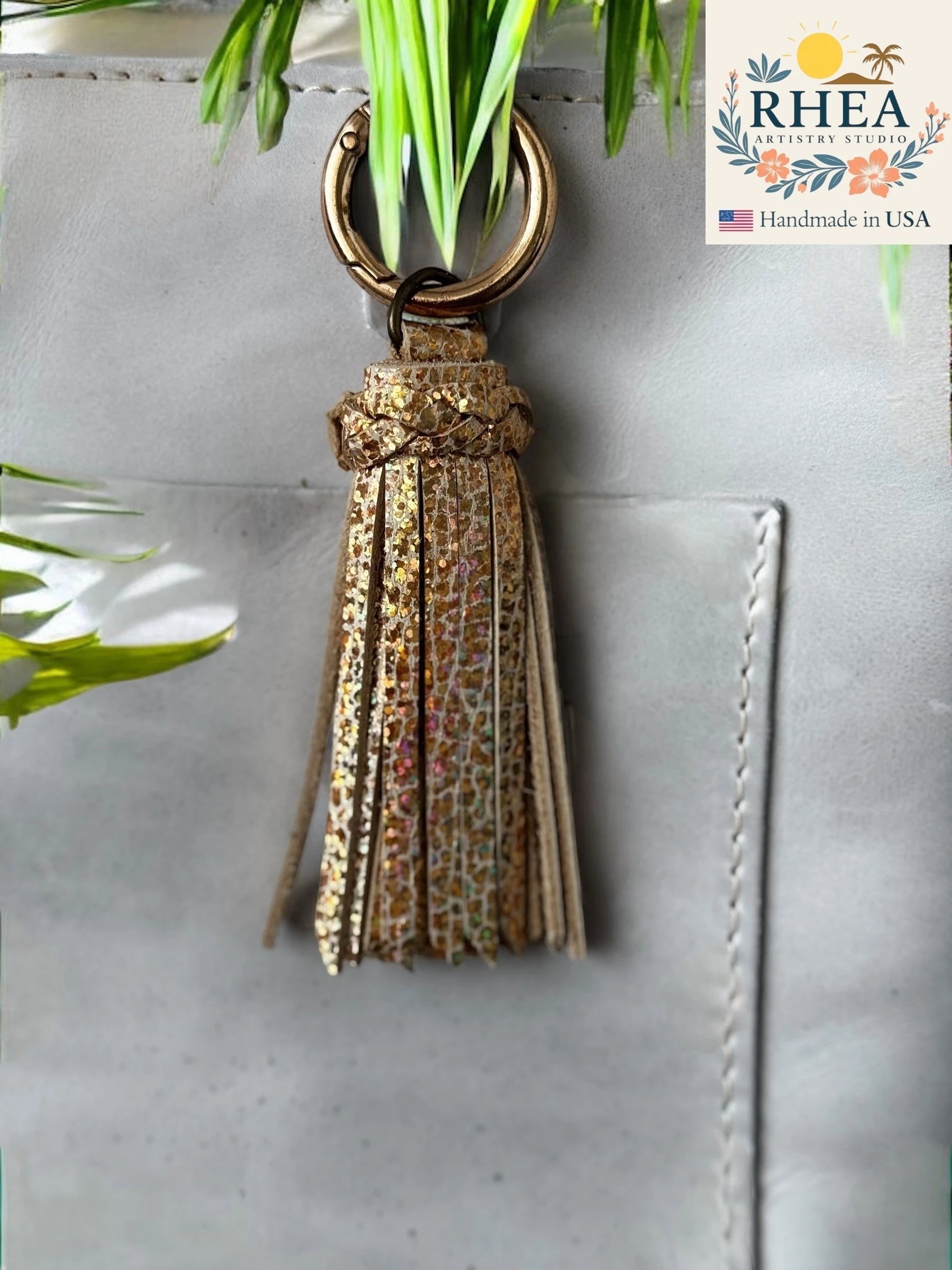 Rhea Artistry Studio handmade gold glitter leather tassel bag charm with lobster clasp.