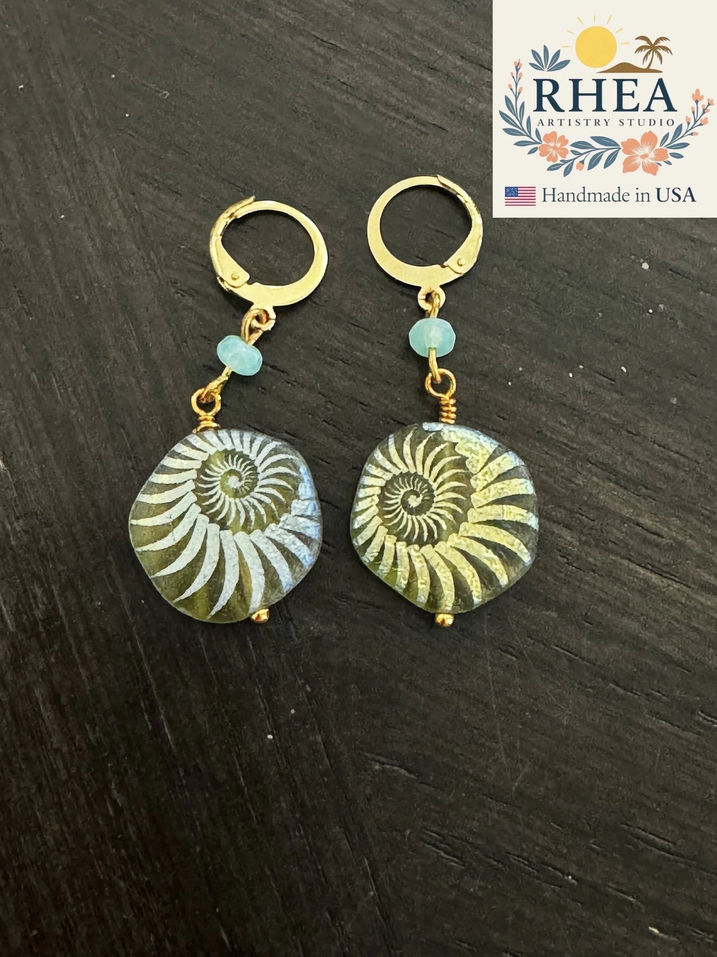 Rhea Artistry Studio gold plated brass earrings with laser etched Czech glass beads in sea foam green, featuring a nautilus shell design.