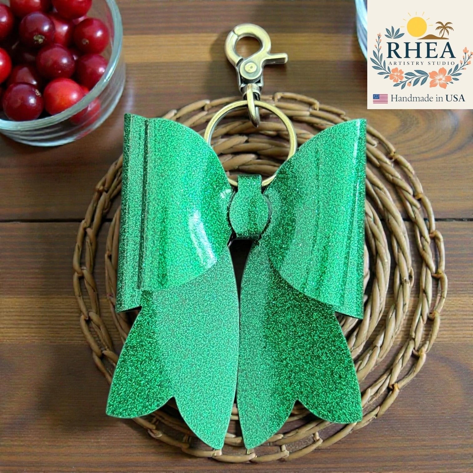 Rhea Artistry Studio handmade green glitter double layer French bow bag charm with brass hardware.