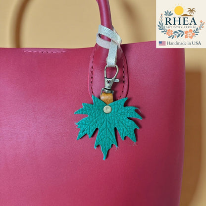 Rhea Artistry Studio green leather maple leaf charm attached to a pink tote bag, autumn collection.