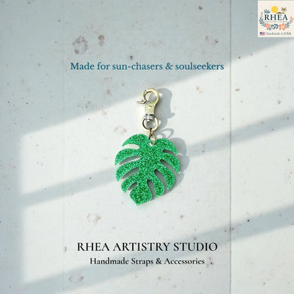 Rhea Artistry Studio green glitter monstera leaf acrylic charm with antique brass clasp, perfect for bags or keys.