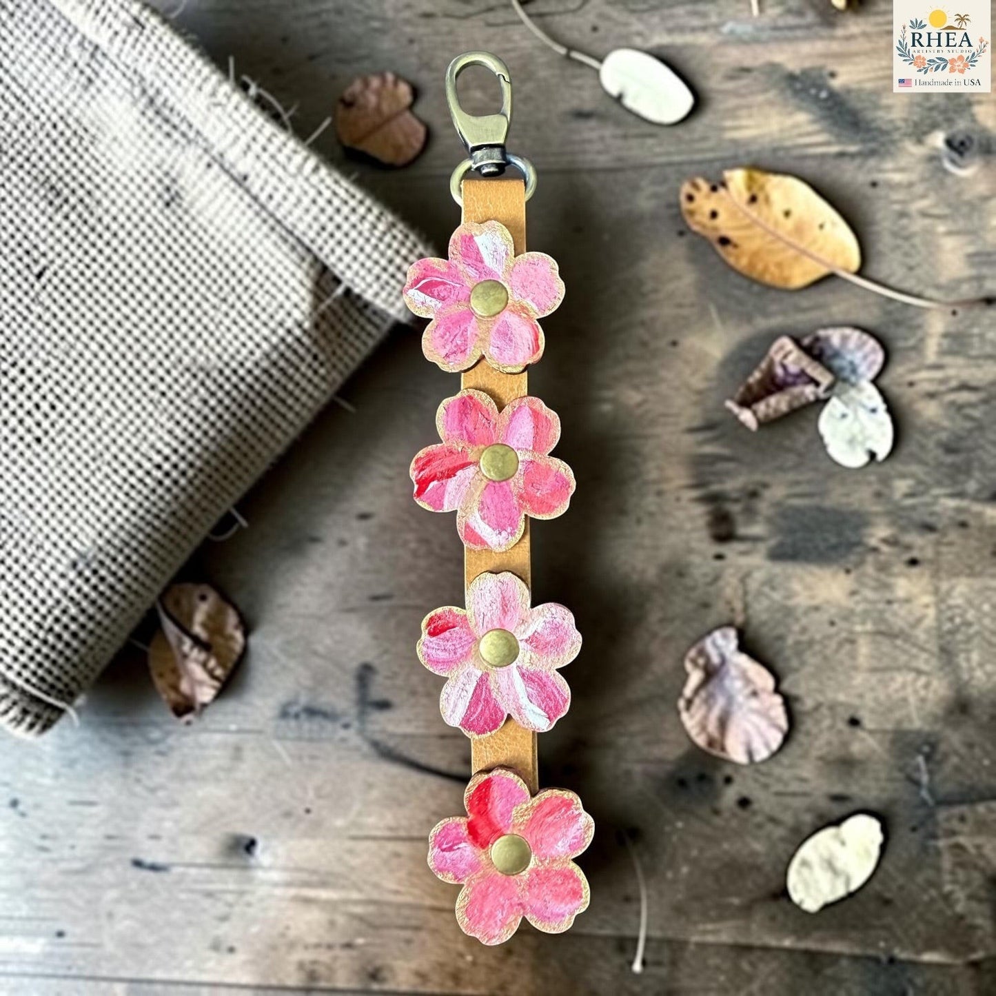 Rhea Artistry Studio Hand-Painted Leather Flower Bag Charm in Berry Blush with sealed painted floral leather charms, brass rivets, and honey leather strap.