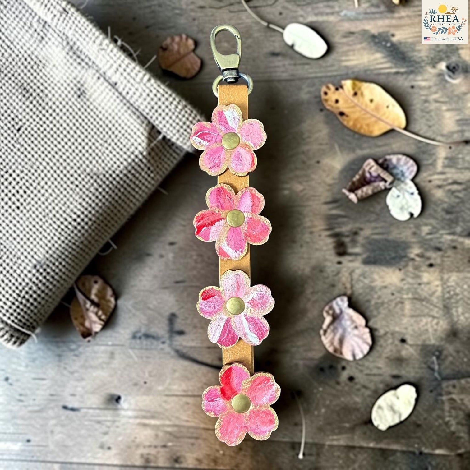 Rhea Artistry Studio Hand-Painted Leather Flower Bag Charm in Berry Blush with sealed painted floral leather charms, brass rivets, and honey leather strap.