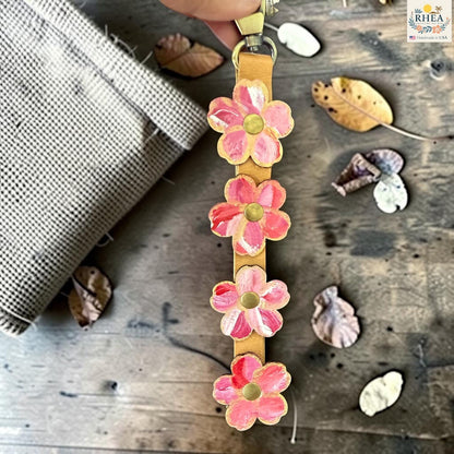 Rhea Artistry Studio Hand-Painted Leather Flower Bag Charm with pink and coral organic flower details, brass rivet centers, and antique brass hardware.