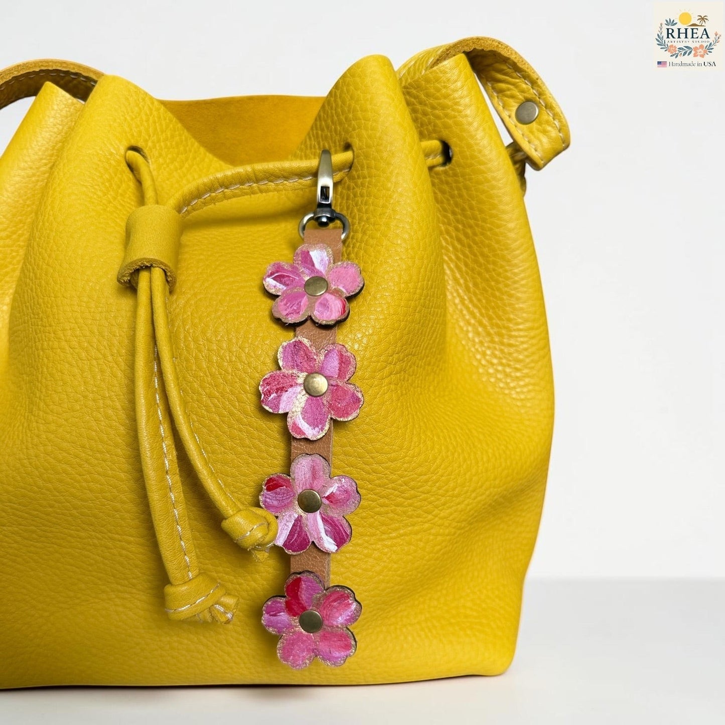 Rhea Artistry Studio Hand-Painted Leather Flower Bag Charm in Berry Blush with pink and coral painted leather flowers, brass rivets, and antique brass clasp.