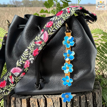 Rhea Artistry Studio Hand-Painted Leather Flower Bag Charm featuring organic painted leather flowers, brass rivets, honey leather strap, and antique brass clasp.