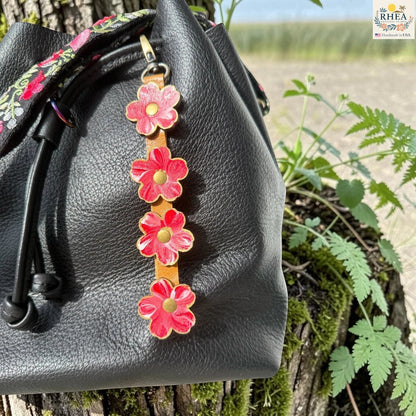 Rhea Artistry Studio Hand-Painted Leather Flower Bag Charm with colorful organic leather flowers, brass hardware, and a lightweight clip-on design for handbags and totes.