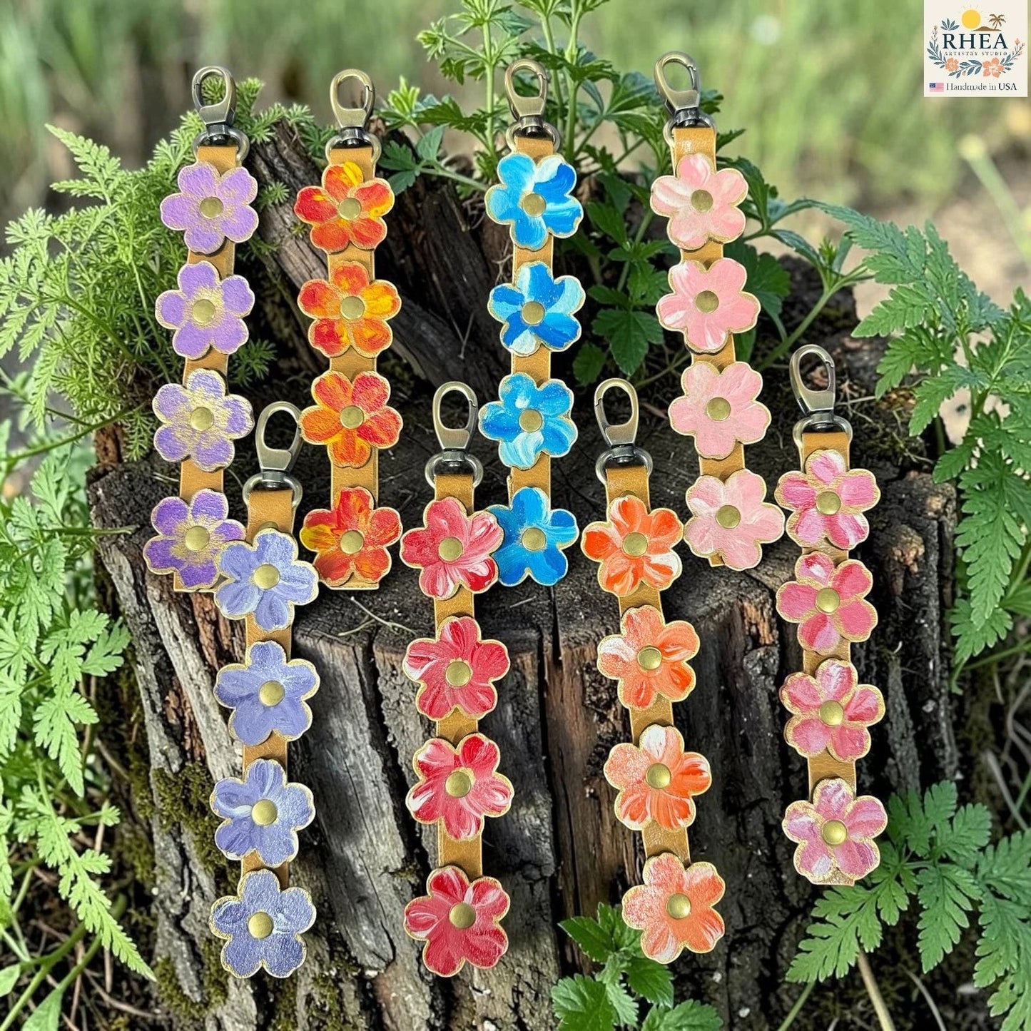 Rhea Artistry Studio handmade hand-painted leather flower bag charm collection in Lavender Honey, Marigold Glow, Blue Sky, Petal Cream, Periwinkle Meadow, Cherry Blush, Coral Honey, and Berry Blush.