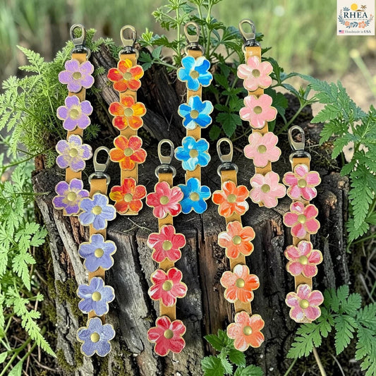 Rhea Artistry Studio handmade hand-painted leather flower bag charm collection in Lavender Honey, Marigold Glow, Blue Sky, Petal Cream, Periwinkle Meadow, Cherry Blush, Coral Honey, and Berry Blush.