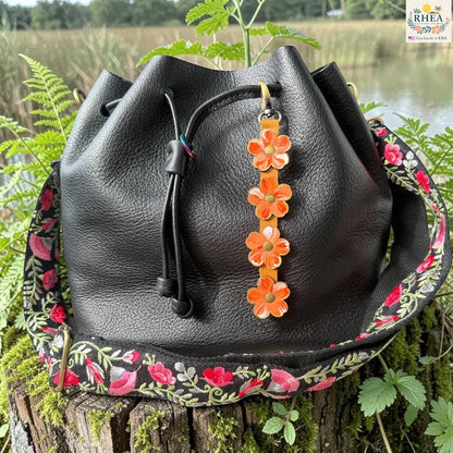Rhea Artistry Studio Hand-Painted Leather Flower Bag Charm in Coral Honey with coral, orange, peach, and white painted leather flowers, brass rivets, honey leather strap, and antique brass clasp.