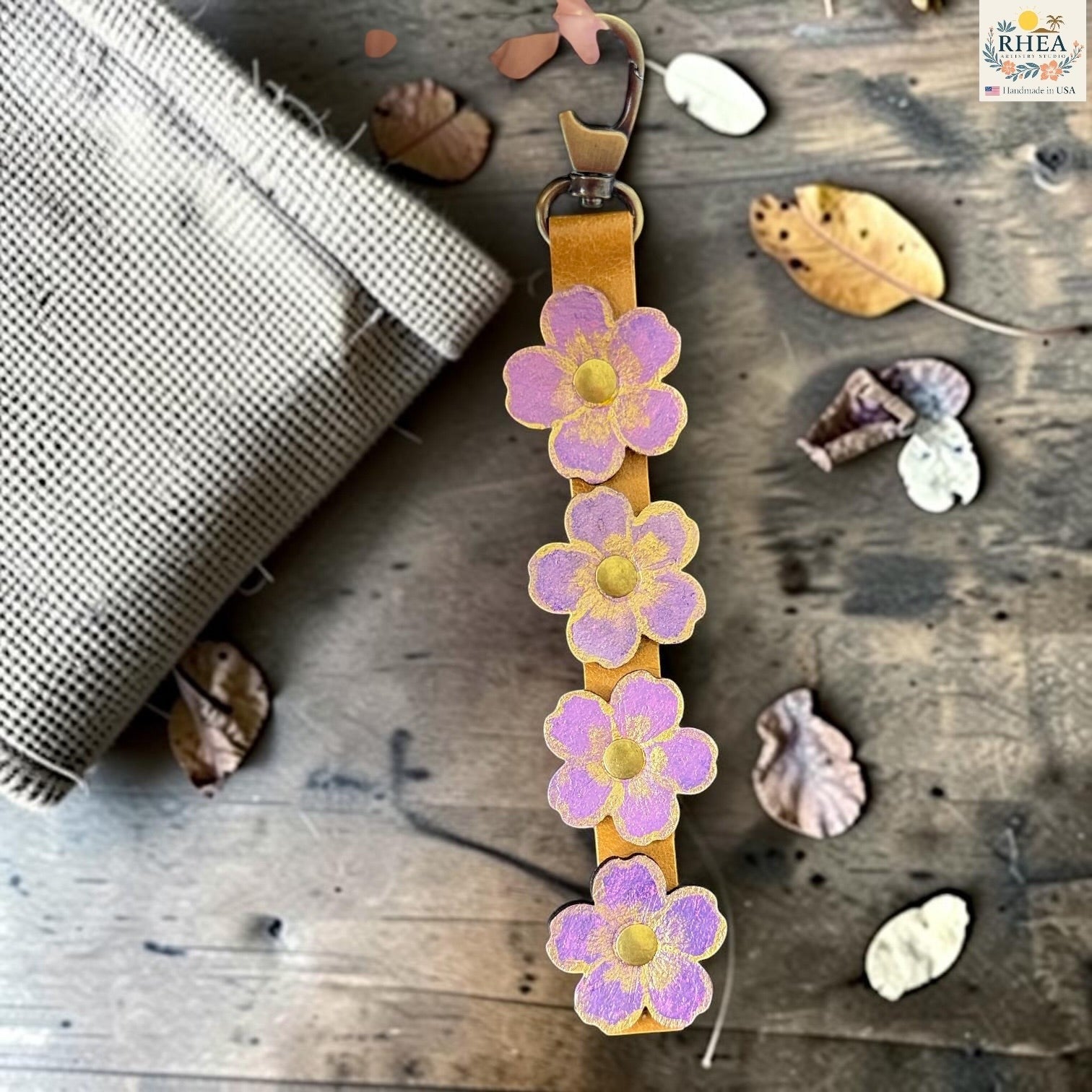 Rhea Artistry Studio Hand-Painted Leather Flower Bag Charm in Lavender Honey with lavender painted leather flowers, brass rivets, and antique brass clasp.