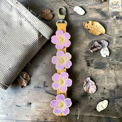 Rhea Artistry Studio Hand-Painted Leather Flower Bag Charm featuring Lavender Honey organic leather flowers with lilac, soft gold, and brass details.