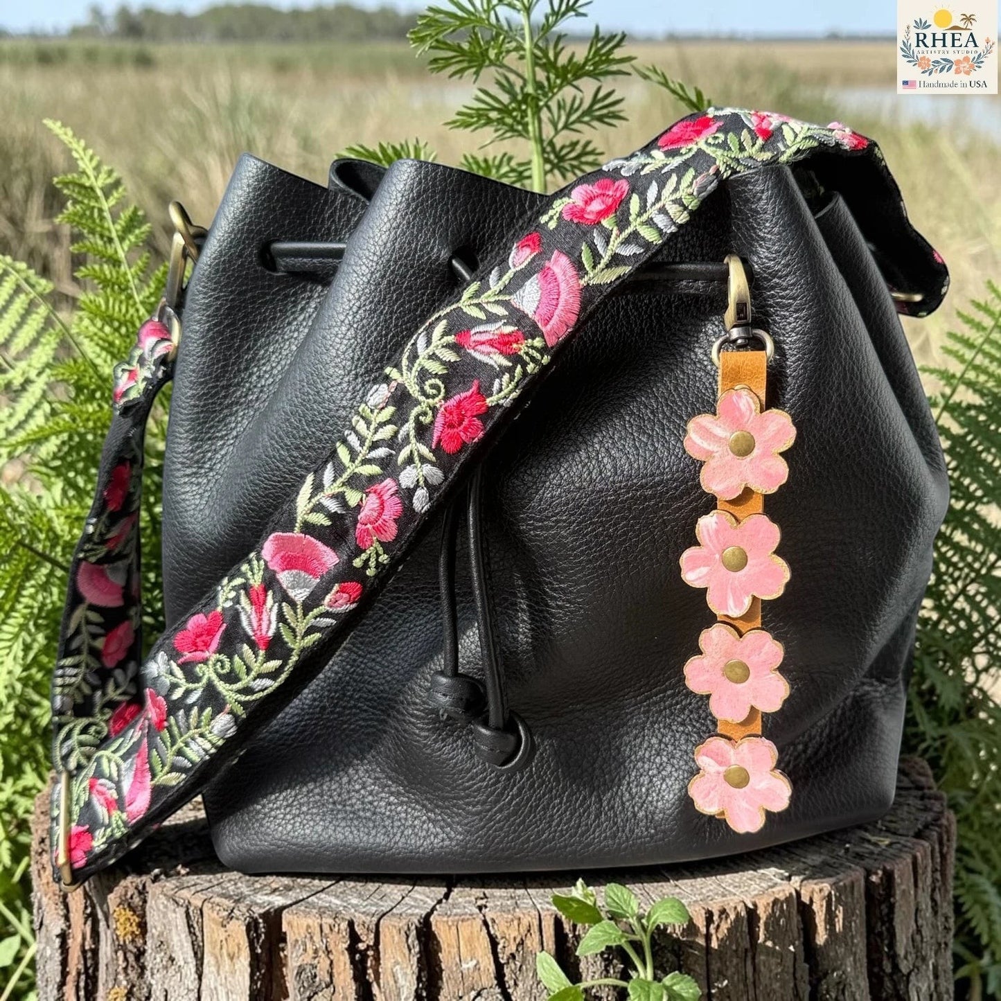 Rhea Artistry Studio Hand-Painted Leather Flower Bag Charm in Petal Cream with soft pale pink and cream painted leather flowers, brass rivets, honey leather strap, and antique brass clasp.