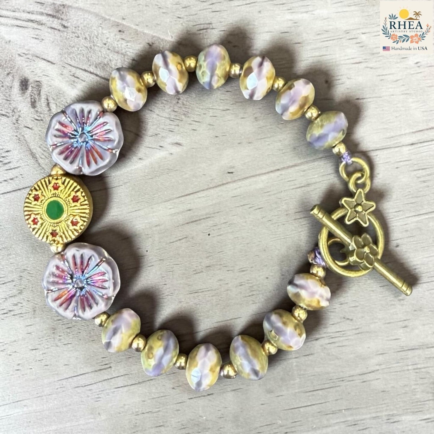 Rhea Artistry Studio handmade bracelet with pastel glass beads, floral accents, and brass toggle clasp.
