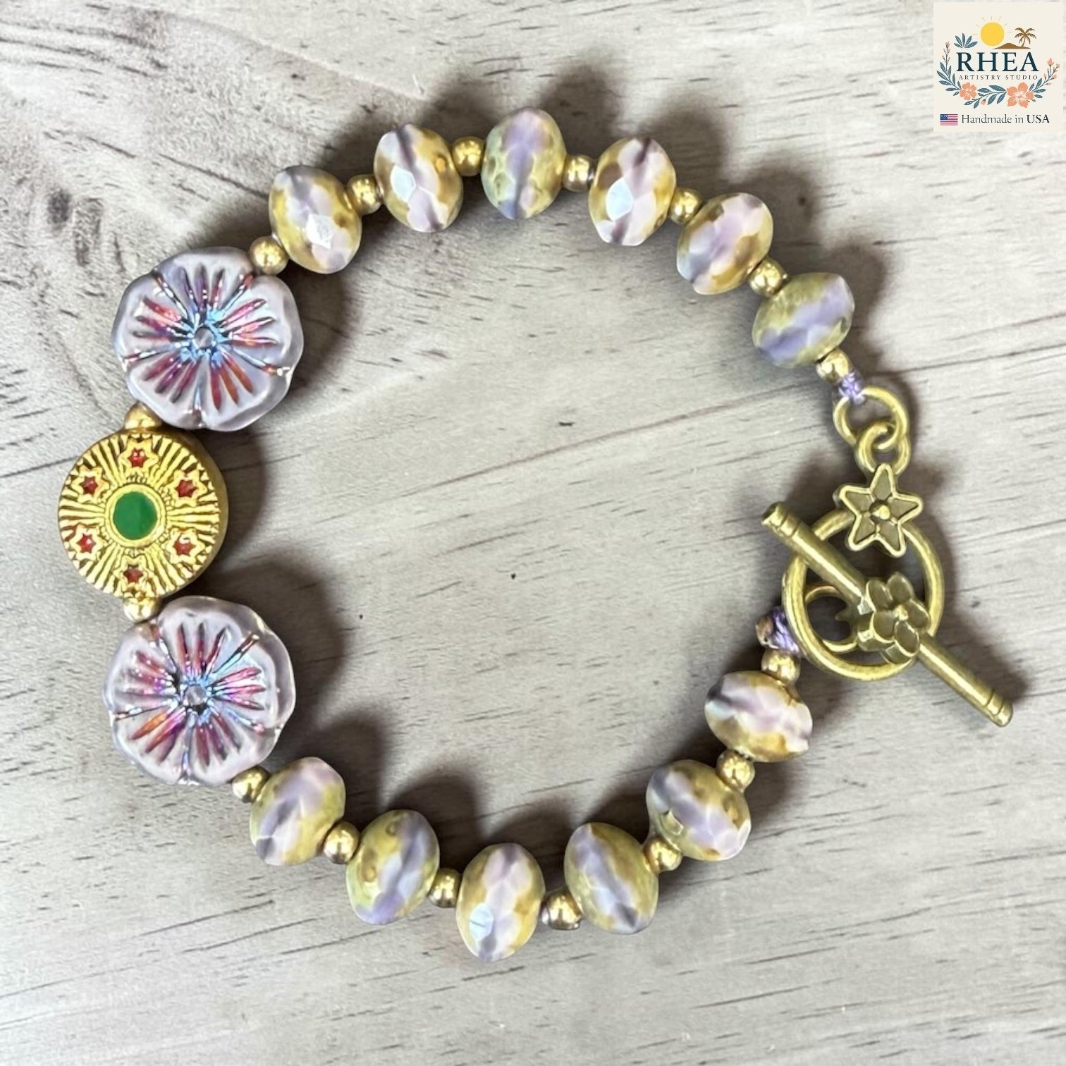 Rhea Artistry Studio handmade bracelet with pastel glass beads, floral accents, and brass toggle clasp.