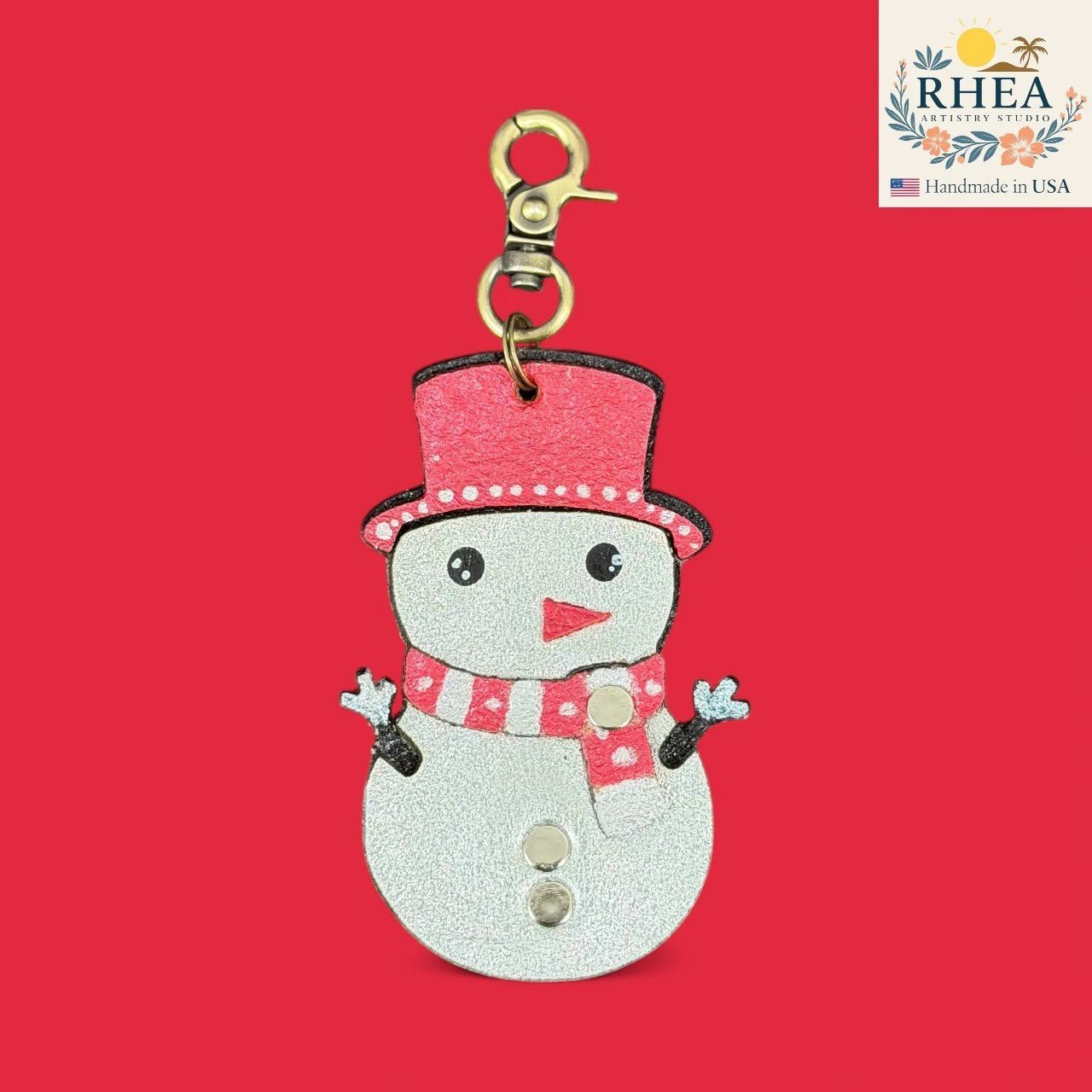 Rhea Artistry Studio handmade leather snowman charm with red hat and scarf, silver body, and festive details.