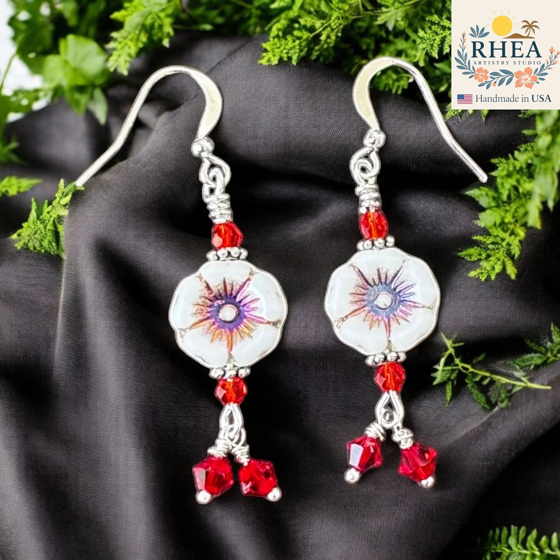 Rhea Artistry Studio white hibiscus floral glass bead earrings with red crystal accents and silver-plated hooks.