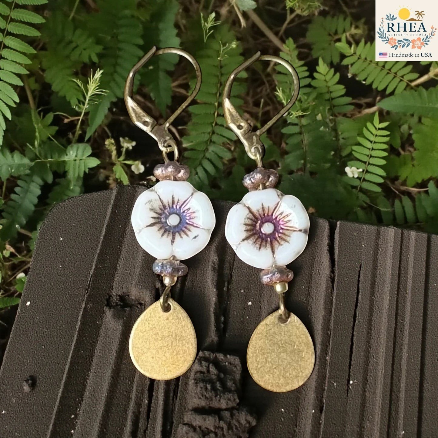 Rhea Artistry Studio white hibiscus glass bead drop earrings with purple accents and brass teardrop charms.