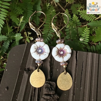 Rhea Artistry Studio white hibiscus glass bead drop earrings with purple accents and brass teardrop charms.