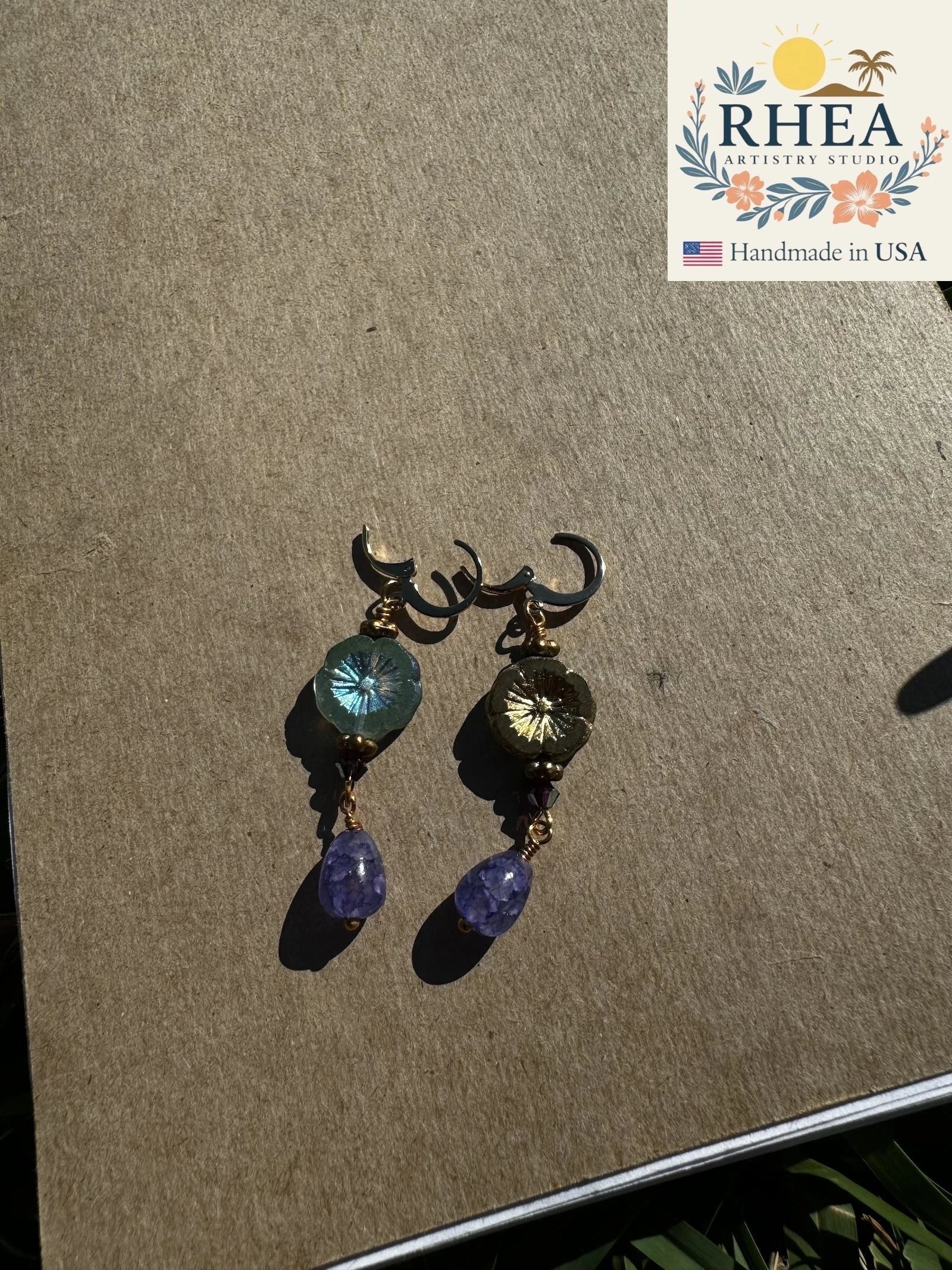Rhea Artistry Studio hibiscus violet drop earrings with 24k gold plated brass, Czech glass, and amethyst gemstones.