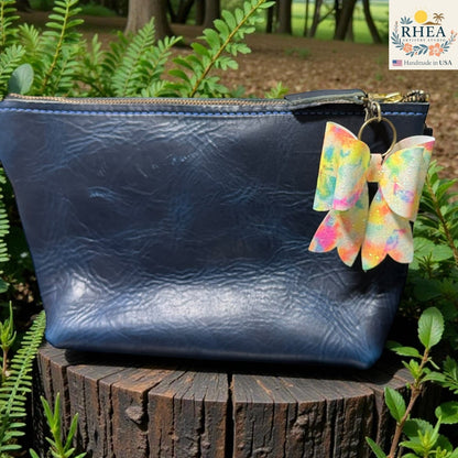 Rhea Artistry Studio handmade double-layer French bow bag charm with holographic tie-dye finish and brass hardware.