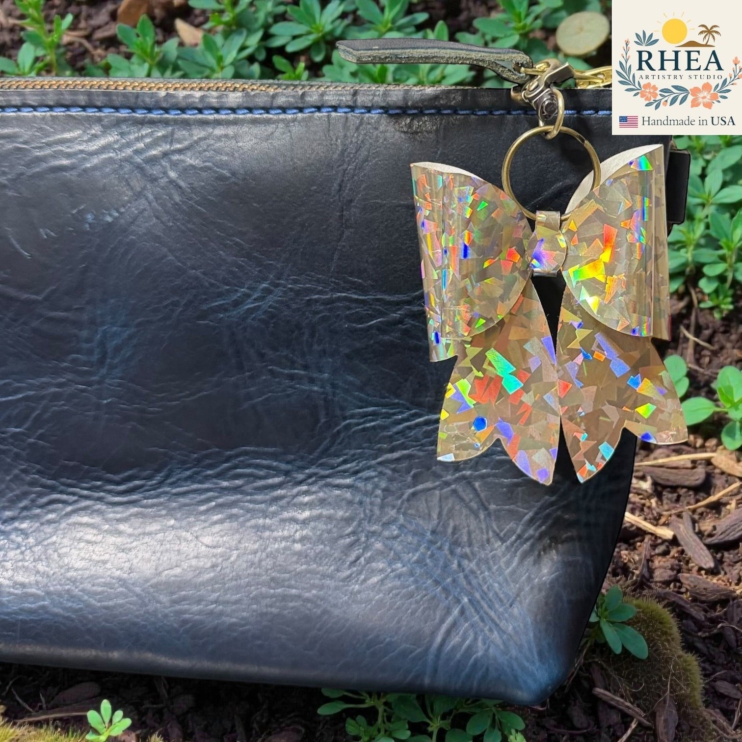 Rhea Artistry Studio holographic bow bag charm with brass hardware, handmade in USA.