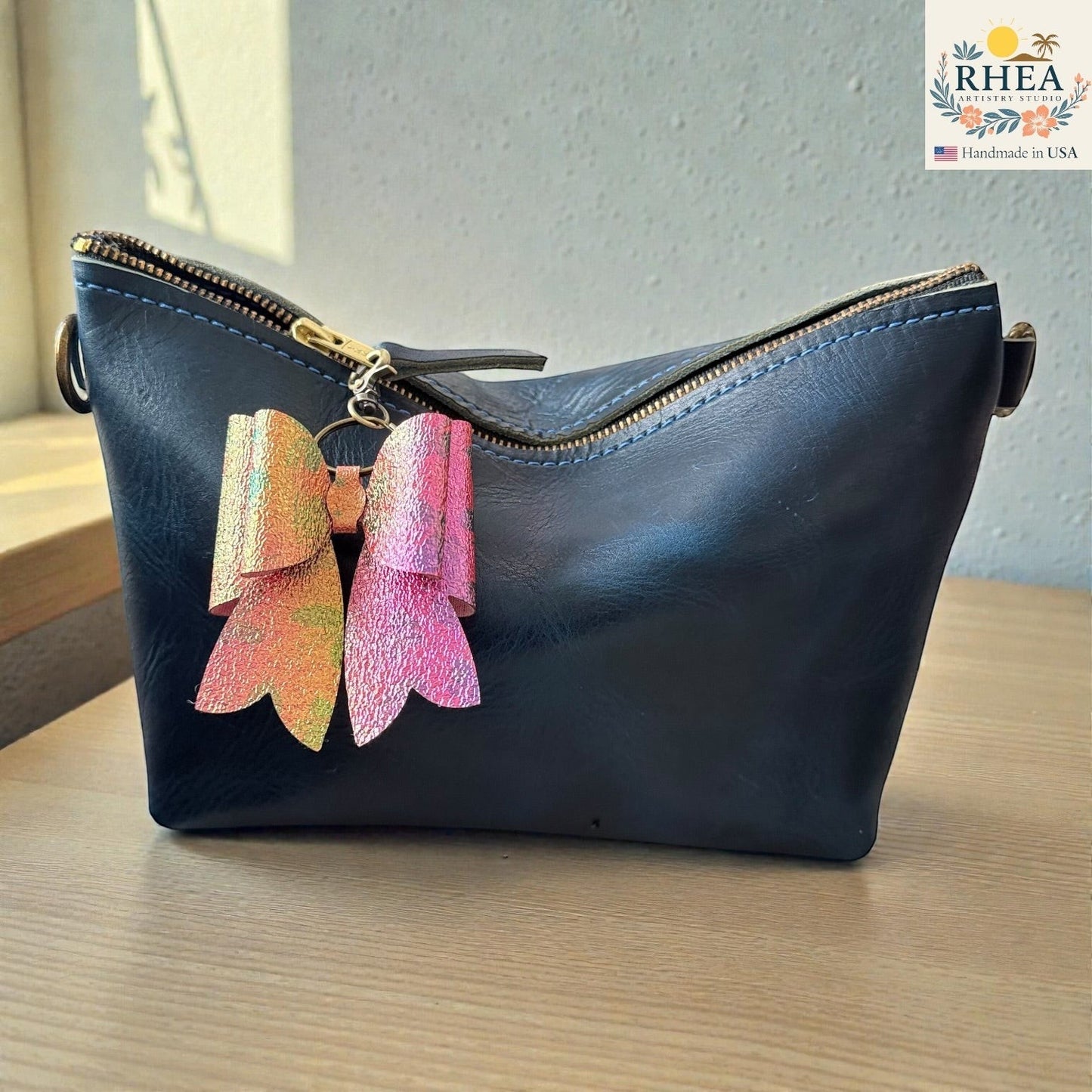 Rhea Artistry Studio handmade holographic pink and orange double-layer French bow bag charm with brass hardware.