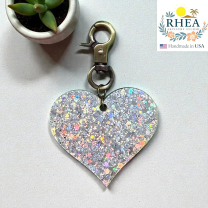 Rhea Artistry Studio holographic glitter heart charm with antique brass clasp, perfect as a zipper pull or bag accent.