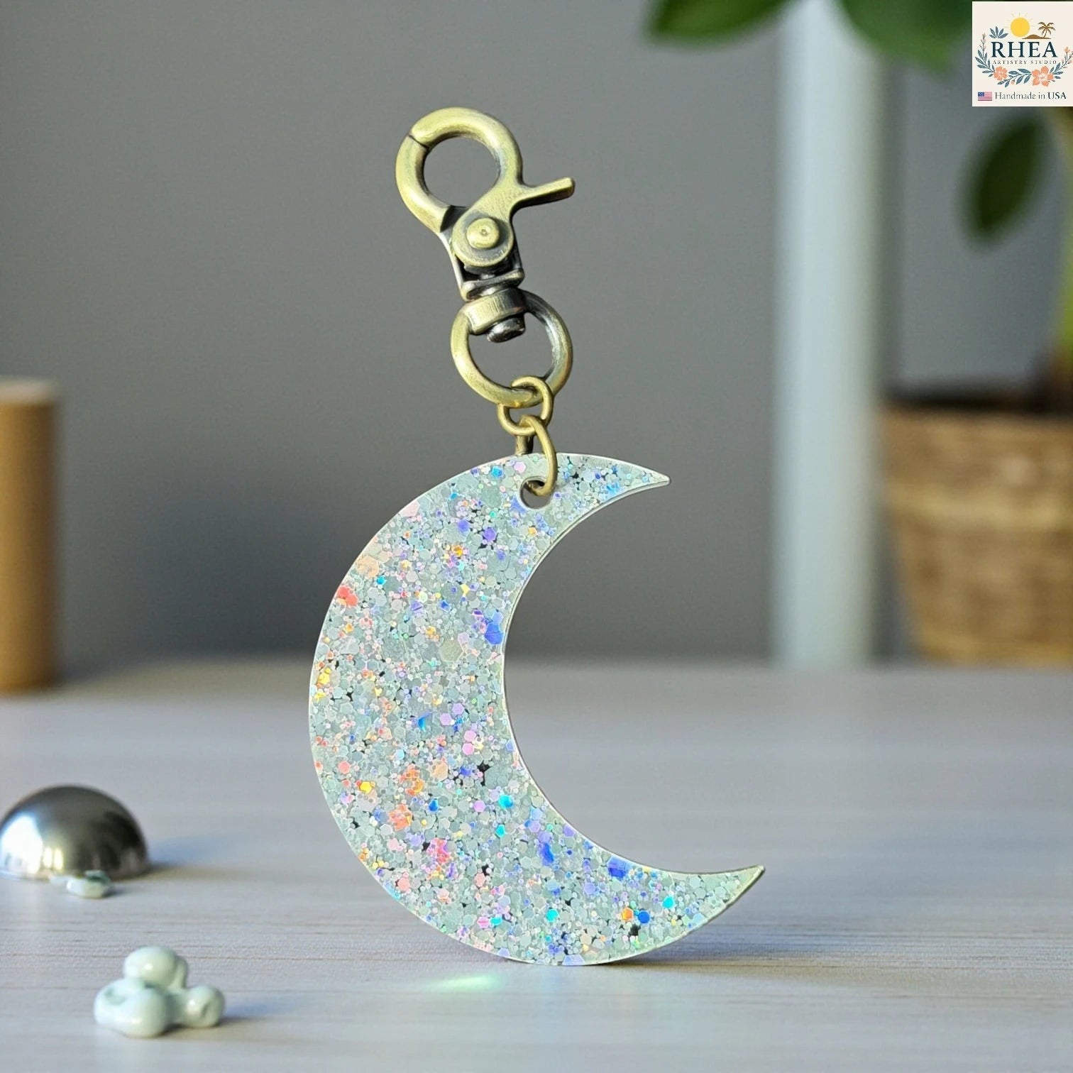 Rhea Artistry Studio holographic glitter moon charm with brass clasp, 2 inches long.
