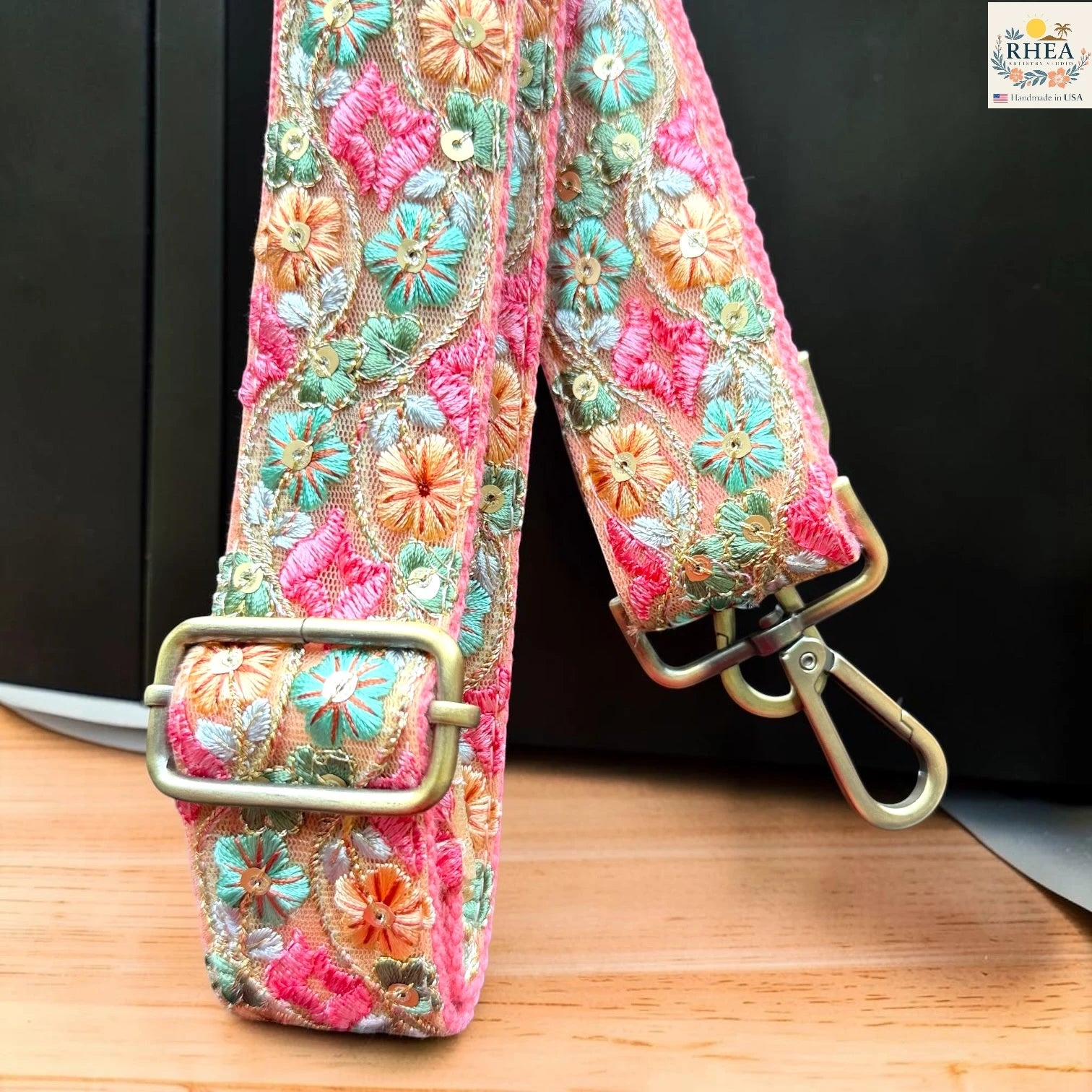 Rhea Artistry Studio ivory crossbody strap with orange, teal, and pink floral embroidery, 1.5-inch width, adjustable length.