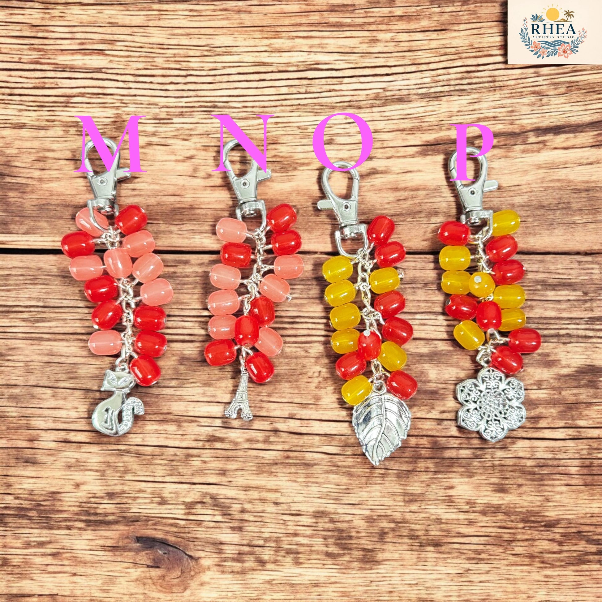Rhea Artistry Studio handmade Jelly Pop keychain with red, pink, and yellow glass beads and silver-tone charms: cat, Eiffel Tower, leaf, and snowflake.