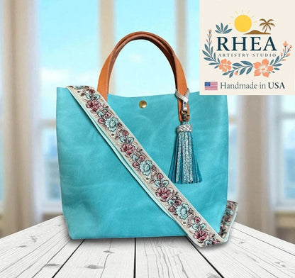 Rhea Artistry Studio lavender and silver embroidered crossbody strap with floral detail on a turquoise tote bag.