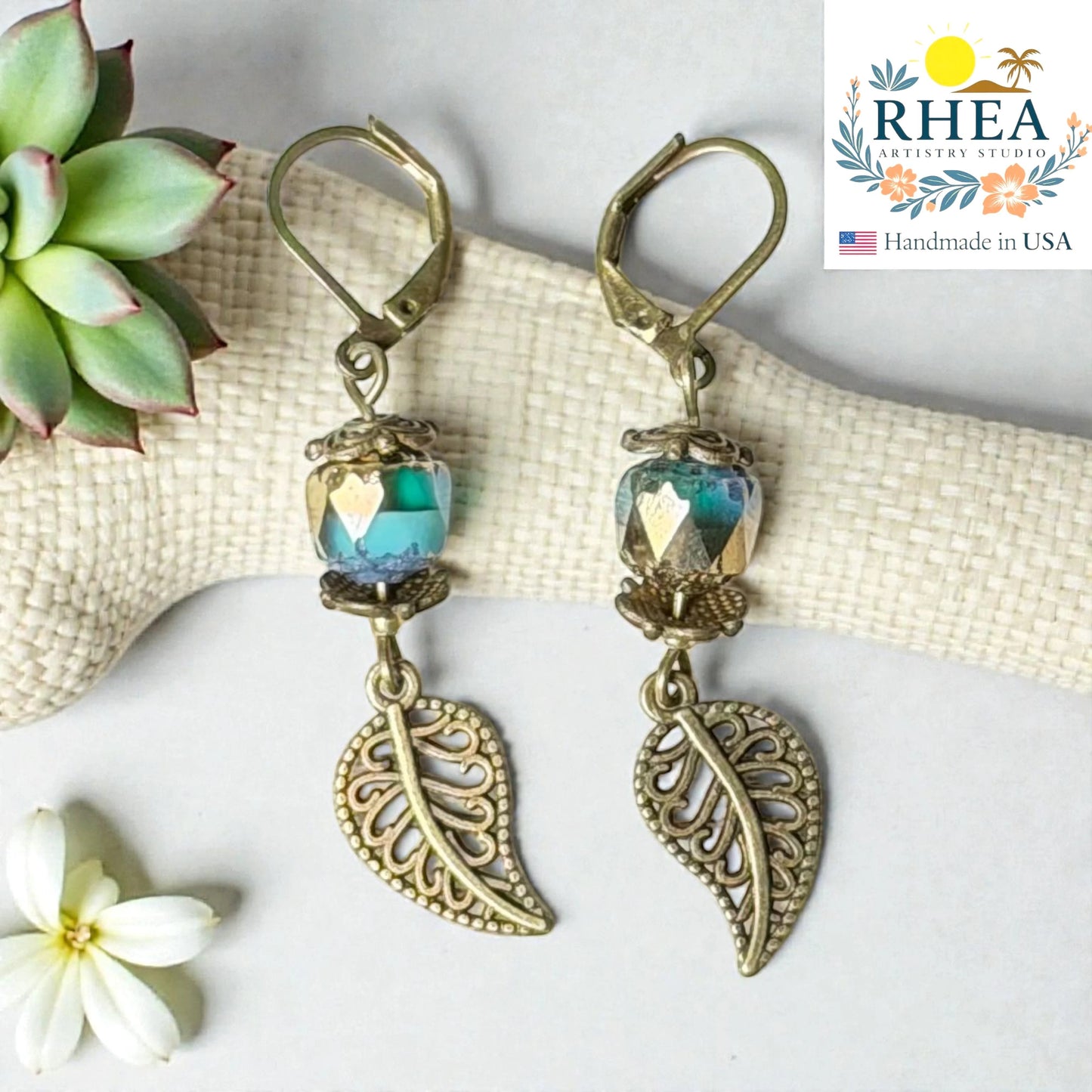Rhea Artistry Studio antique brass leaf drop earrings with faceted blue-green glass beads, 2 inches long.