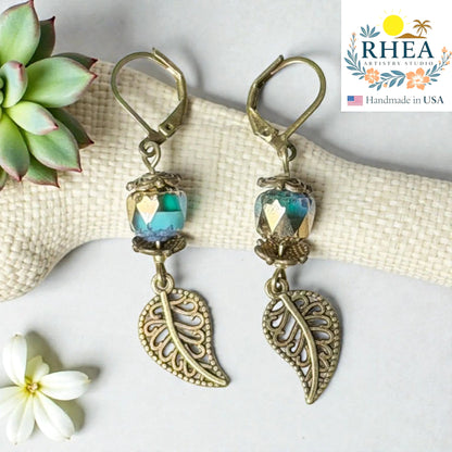 Rhea Artistry Studio antique brass leaf drop earrings with faceted blue-green glass beads, 2 inches long.
