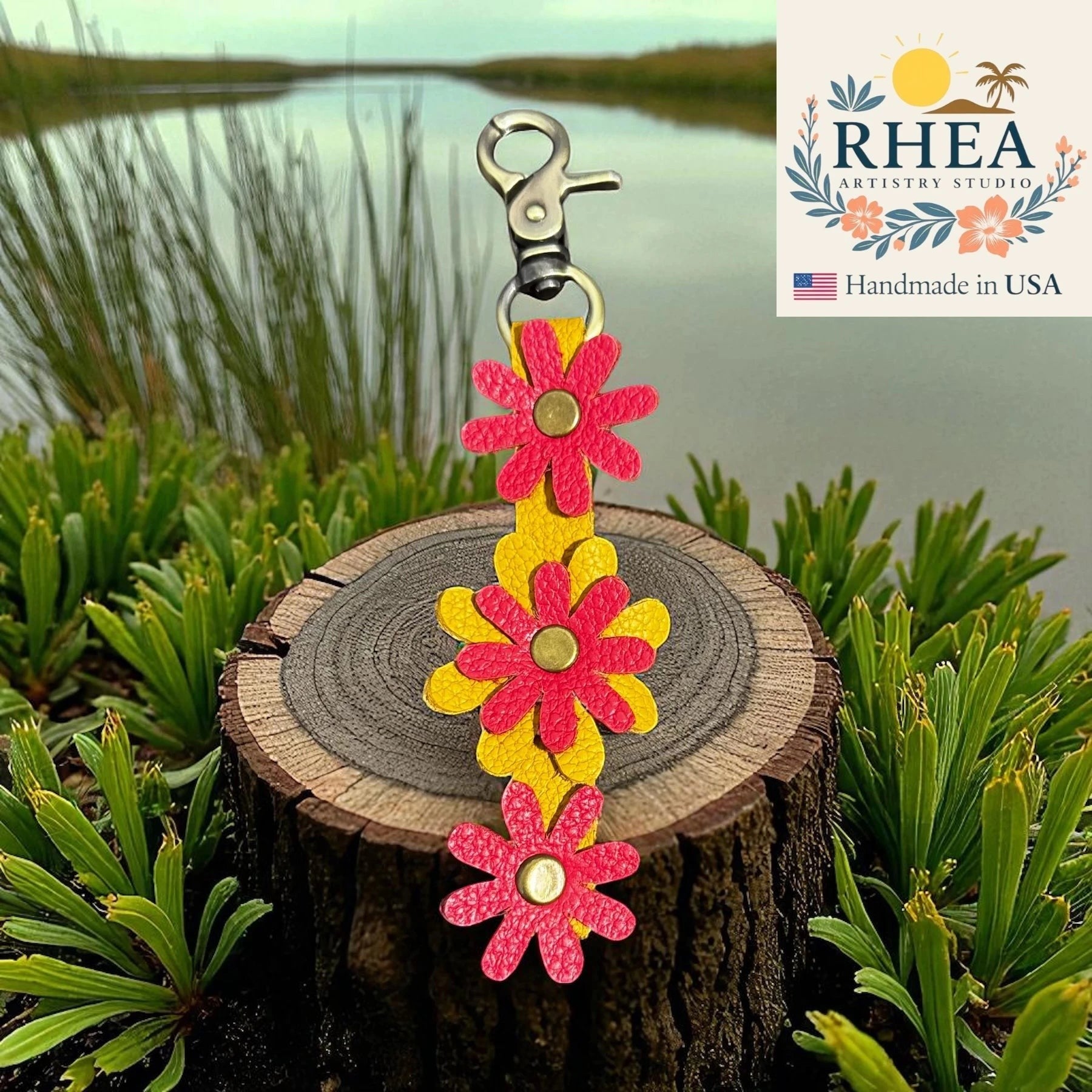 Rhea Artistry Studio yellow leather keychain with layered pink daisy charms and brass accents, 5 inches long.